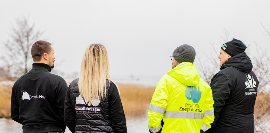 Fyra personer från bromöllabolagen står med ryggen mot kameran och diskuterar 