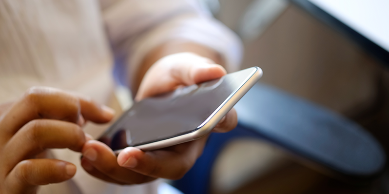 En man håller en mobiltelefon i handen